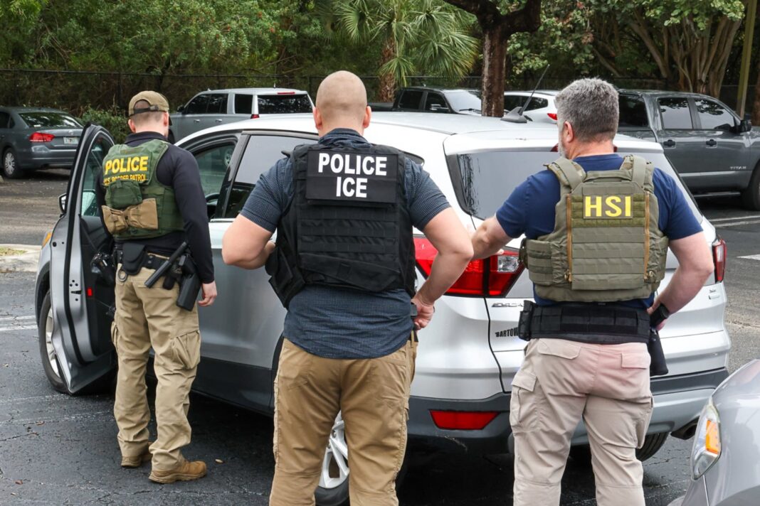 Agentes del ICE realizan una detención junto a un automóvil con la ventanilla rota, en una calle de Bridgeton, Nueva Jersey.