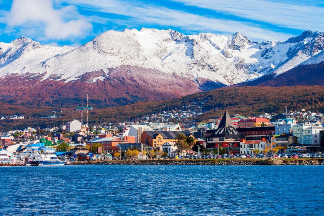Vista panorámica de Ushuaia con el Canal de Beagle y montañas, representando el desarrollo inmobiliario y turístico.